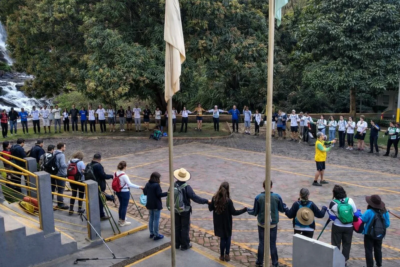 Participantes reunidos em círculo próximo a uma cachoeira
