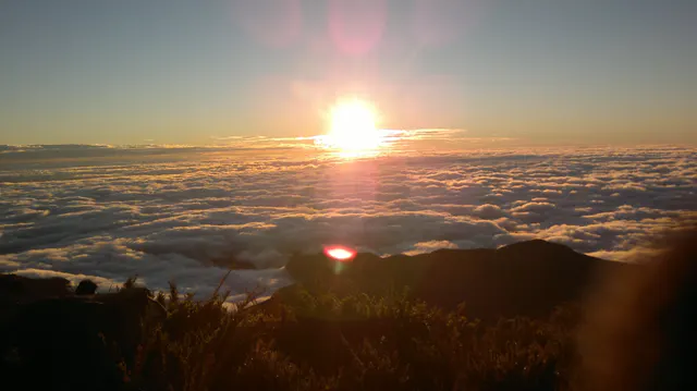 Sol sobre um mar de nuvens entre montanhas