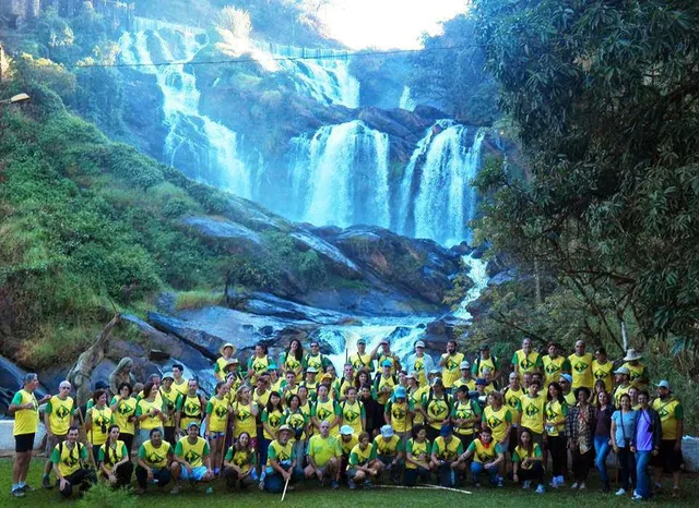 Grupo de pessoas diante de uma cachoeira